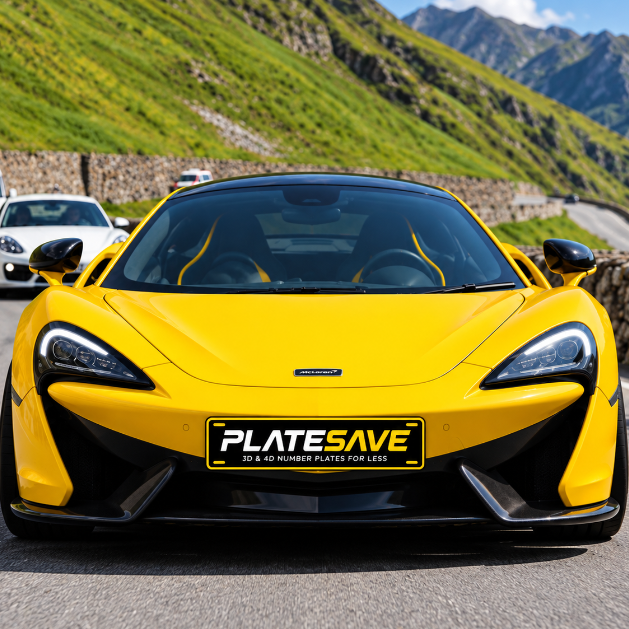 A bright yellow sports car photographed from the front on a mountain road, with a black license plate frame reading PLATESAVE mounted on the front. The background shows green hills and mountains under a blue sky.