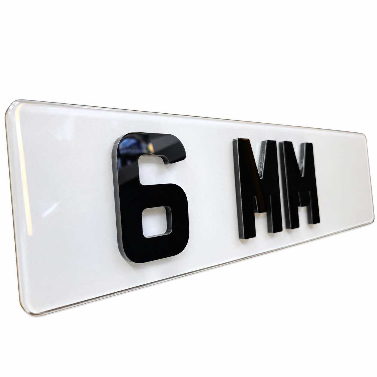 A glossy white rectangular license plate or plate-style sign with raised black characters reading '6 MM' on a clean white background.