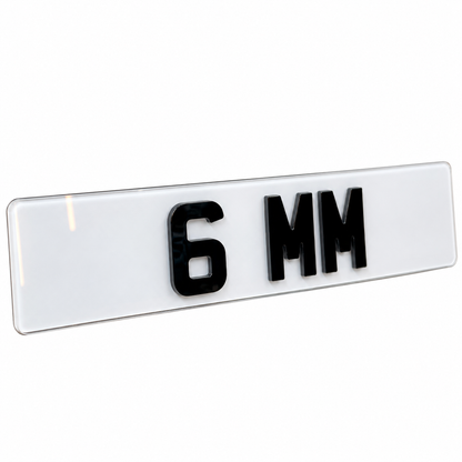 A glossy white rectangular license plate blank with raised black '6 MM' lettering, shown at an angle on a plain white background.
